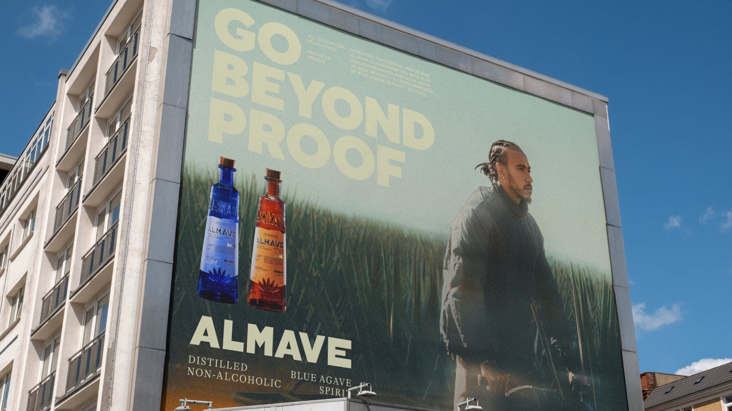 Building with large billboard showing Lewis Hamilton in agave field. Go beyond proof. Almave. 2 bottles of Almave Spirits