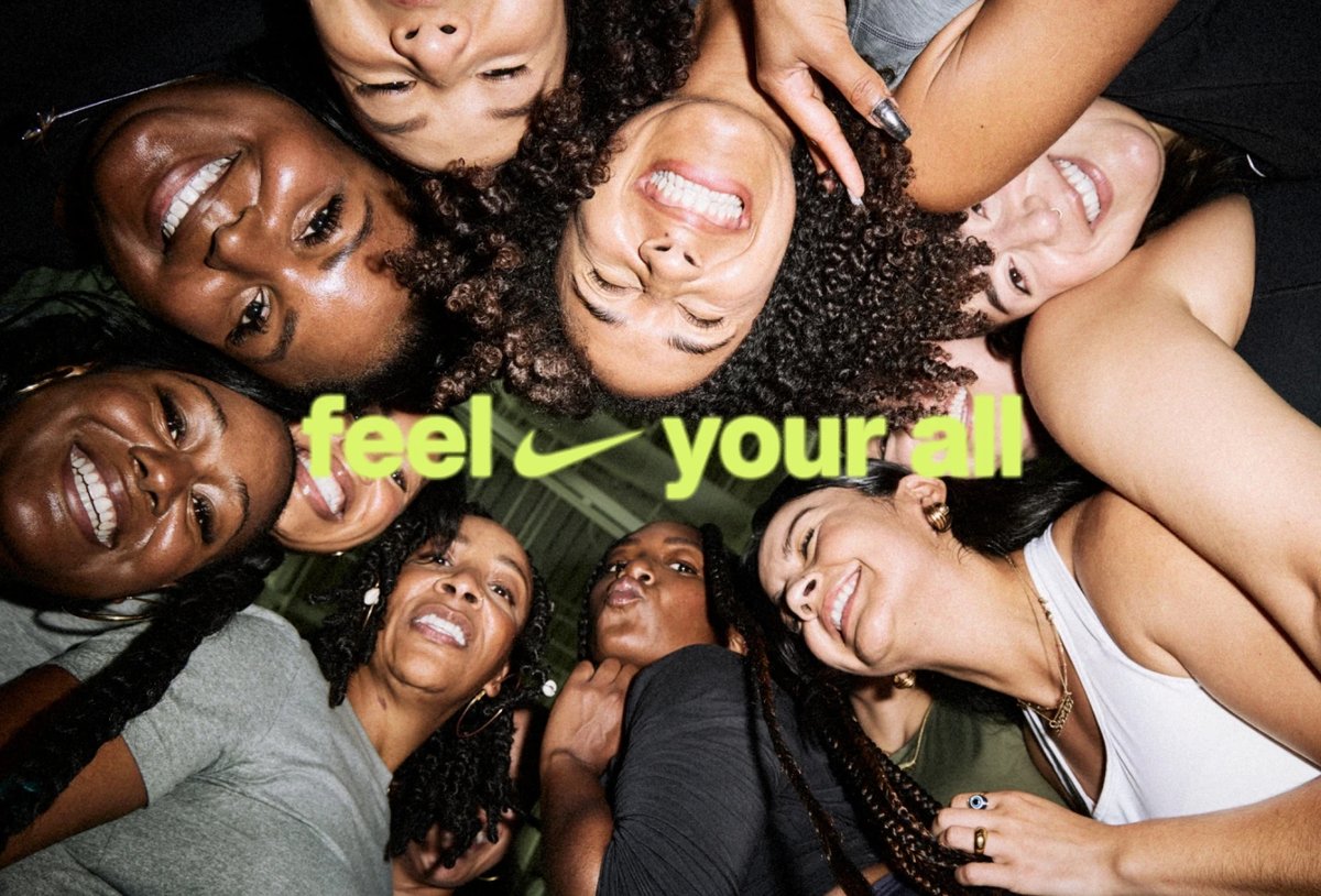 A group of women stand in a circle, smiling down at the camera. The text "feel your all" with a Nike swoosh appears across the center.