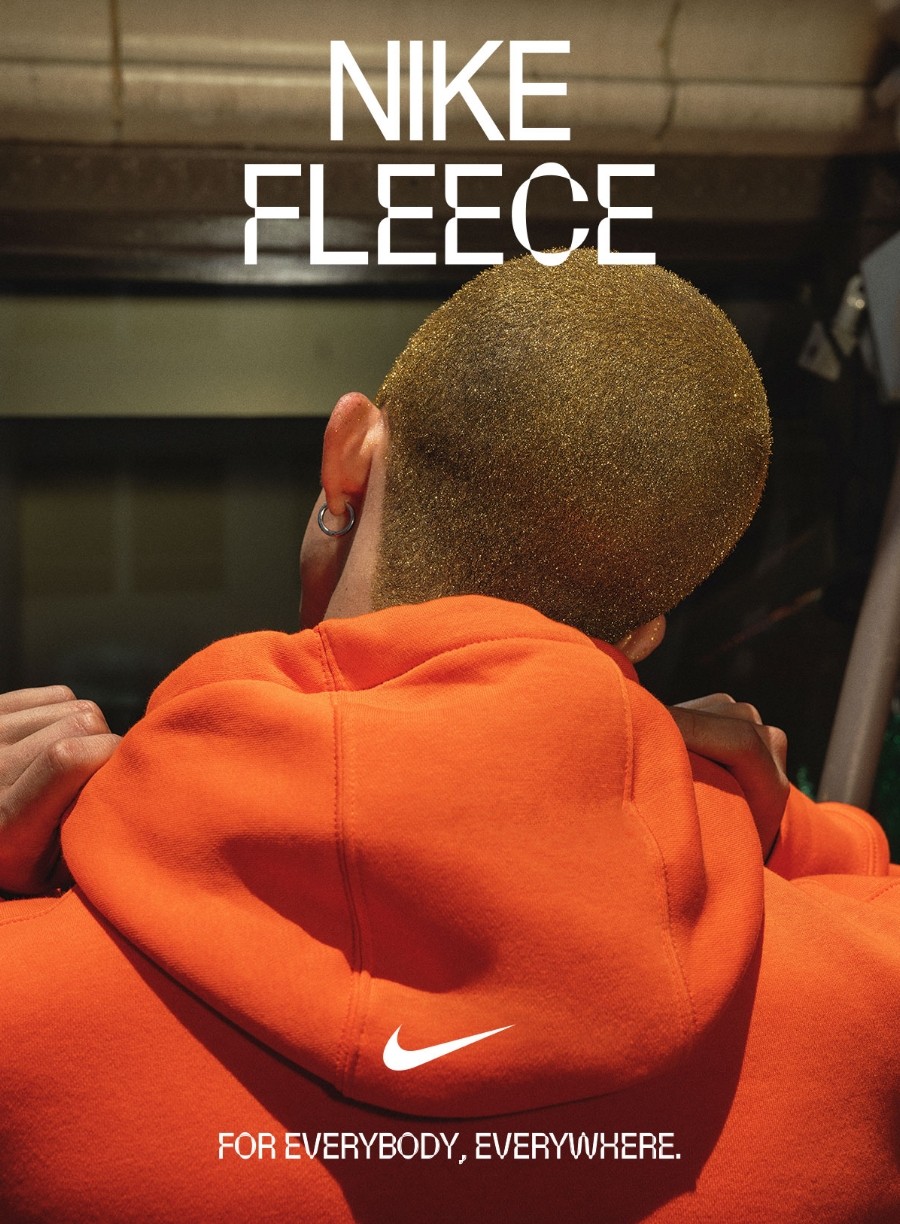 Nike Fleece - For everybody everywhere. Back of man wearing orange hooded sweatshirt.