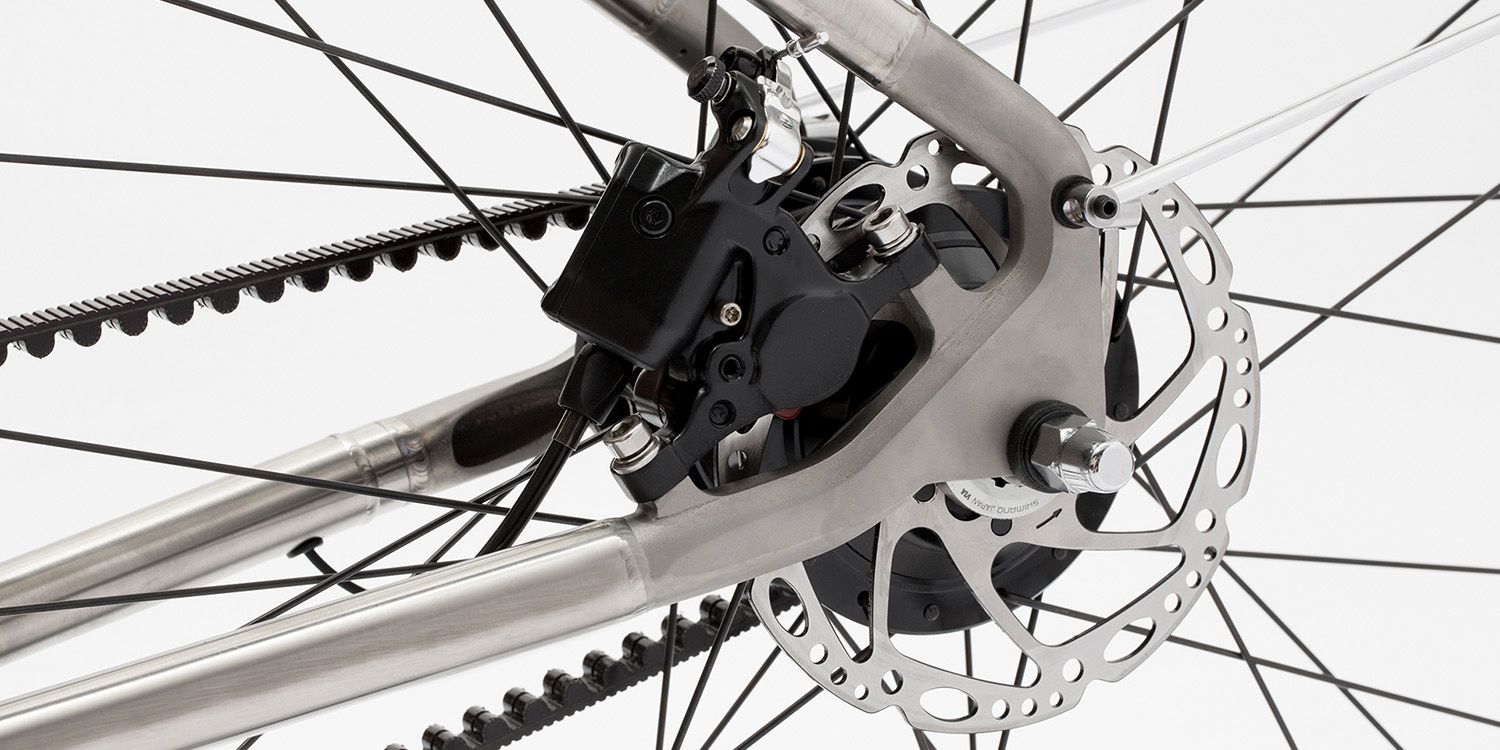 Close-up of a bicycle's rear wheel showing the disc brake, derailleur, and sprocket against a solid white background.