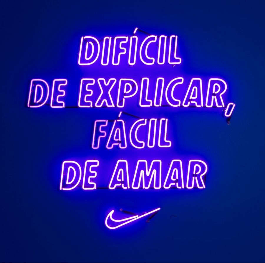 Neon sign reads dificil de explicar, facil de amar with Nike swoosh.