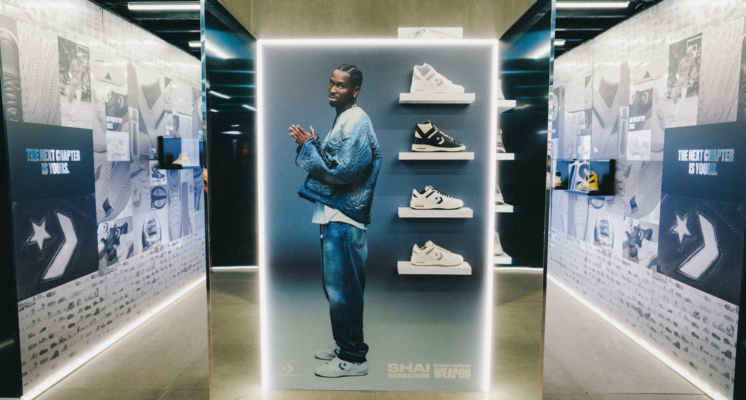 display wall with Shai Gilgeous-Alexander printed on it. Four Converse sneakers are displayed on the wall. Text on wall reads Shai Gilgeous-Alexander Converse Choose your weapon.