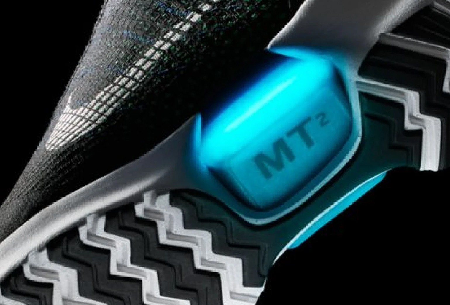 Close-up of a sneaker sole featuring a glowing blue area labeled "MT²" and a zigzag tread pattern.