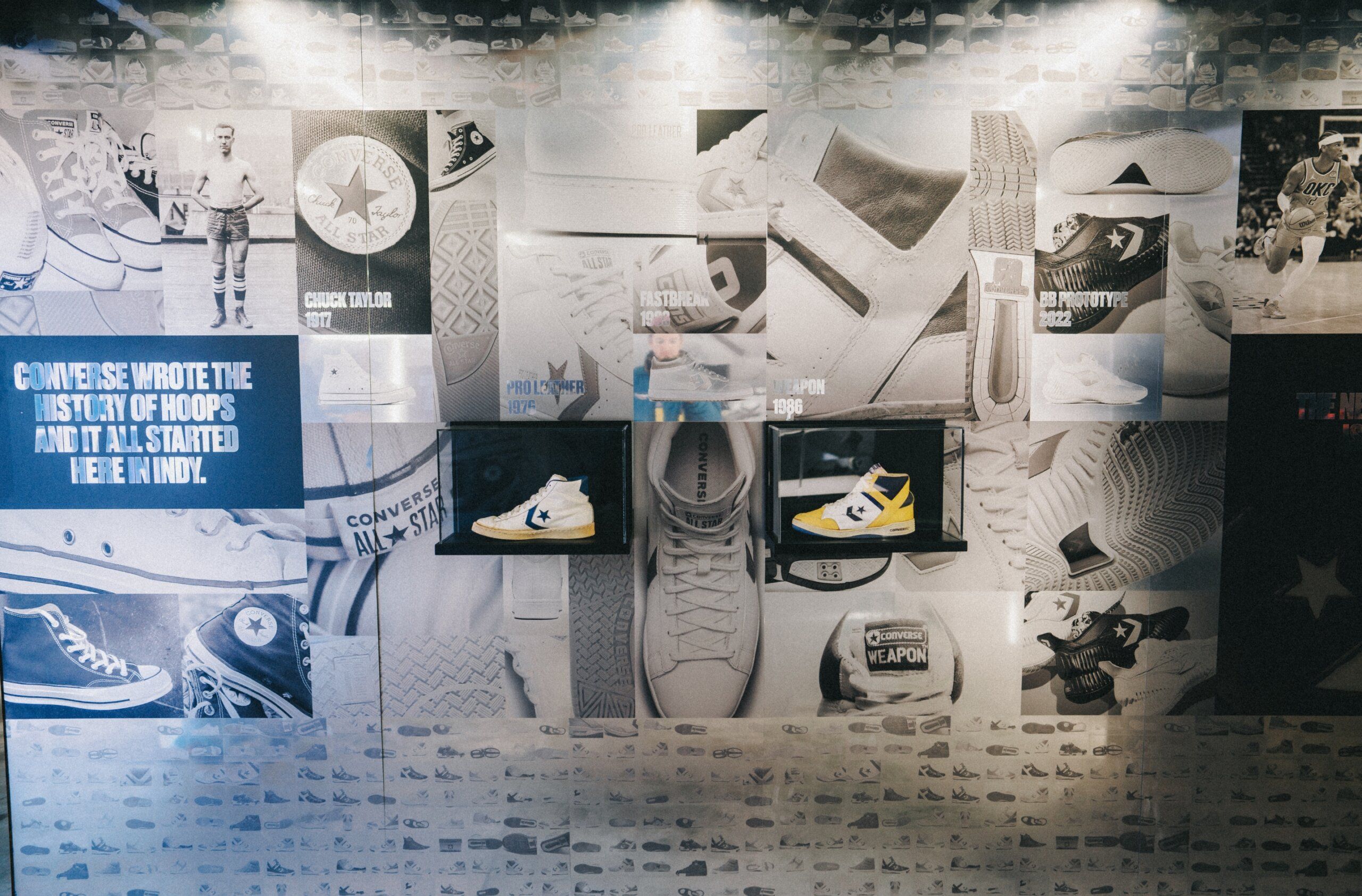 Wall collage of historic Converse sneakers and players. Text reads Converse wrote the history of hoops and it all started here in INDY.