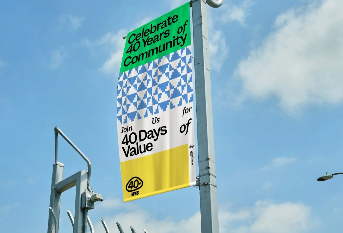 A vertical street banner reads "Celebrate 40 Years of Community. Join Us for 40 Days of Value," with geometric patterns and bright colors against a blue sky.
