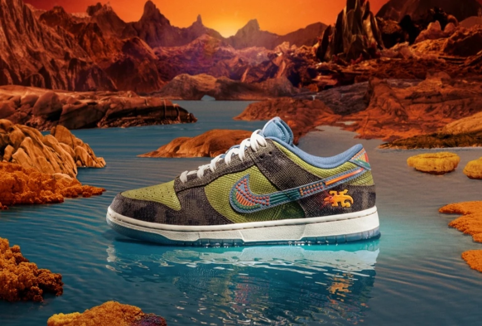 A colorful sneaker with blue, green, and orange accents is displayed against a surreal, rocky landscape with water and a vivid orange sky.