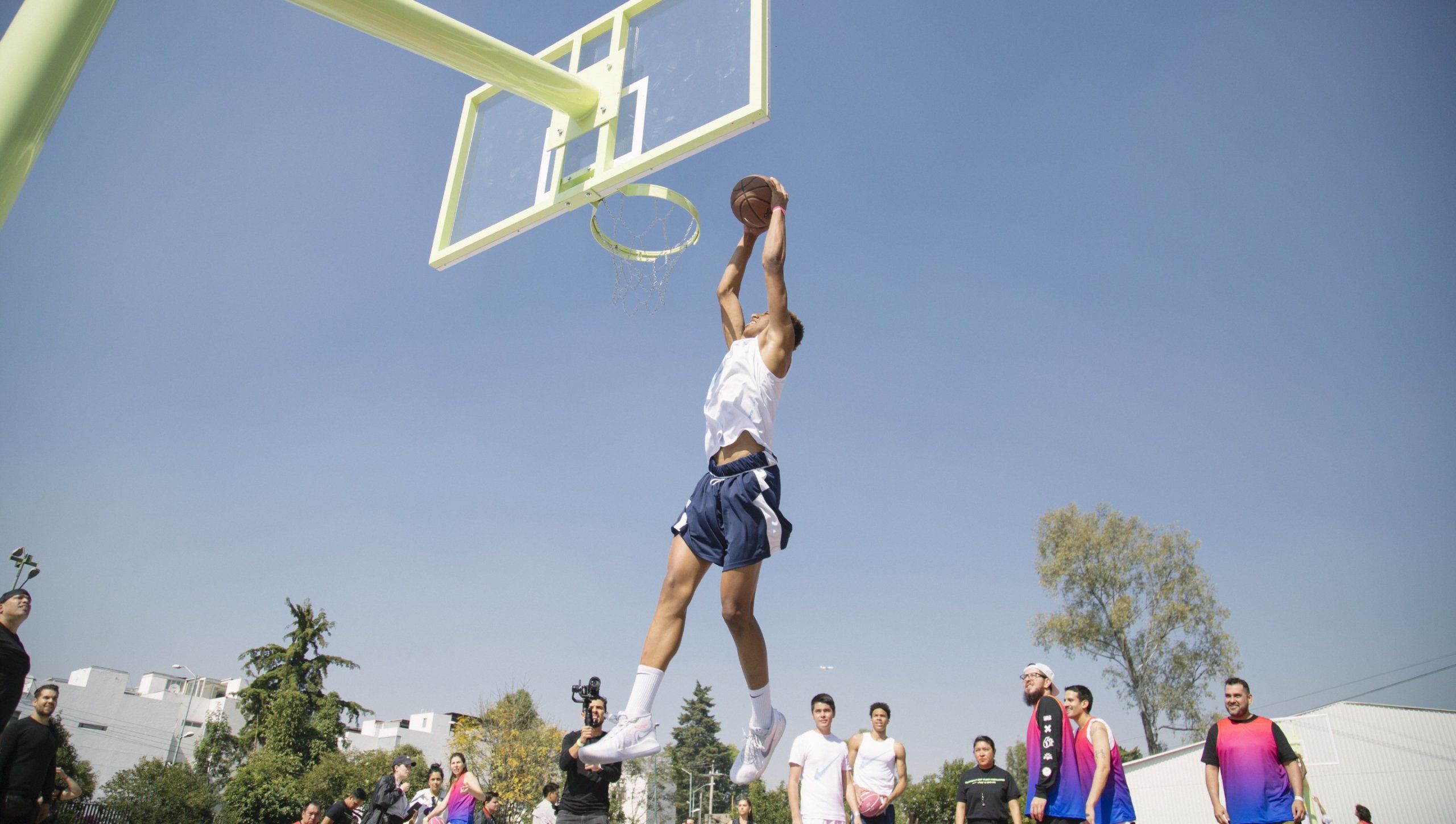 Man slam dunks basketball on outdoor basketball court