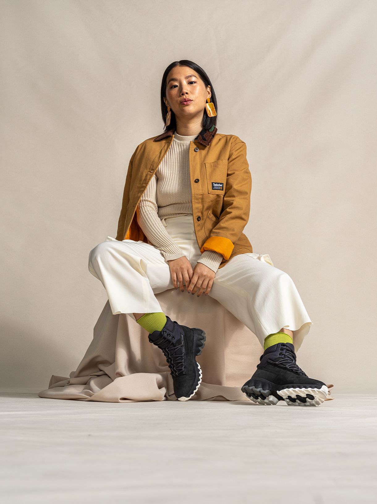 Sophia Li sitting wearing tan Timberland jacket and black Timberland Edge Greenstride boots