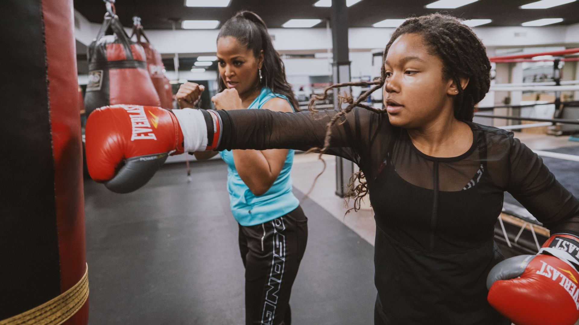 2 women boxers training on punching bag