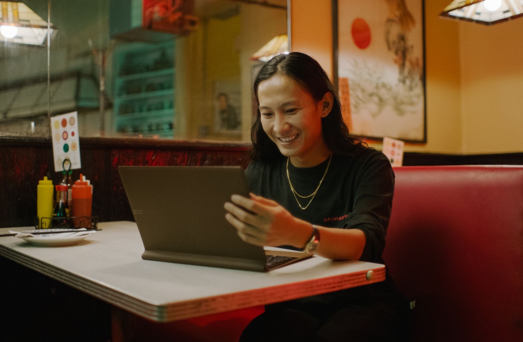 Alexander Wang sitting in resaurant smiling using HP laptop