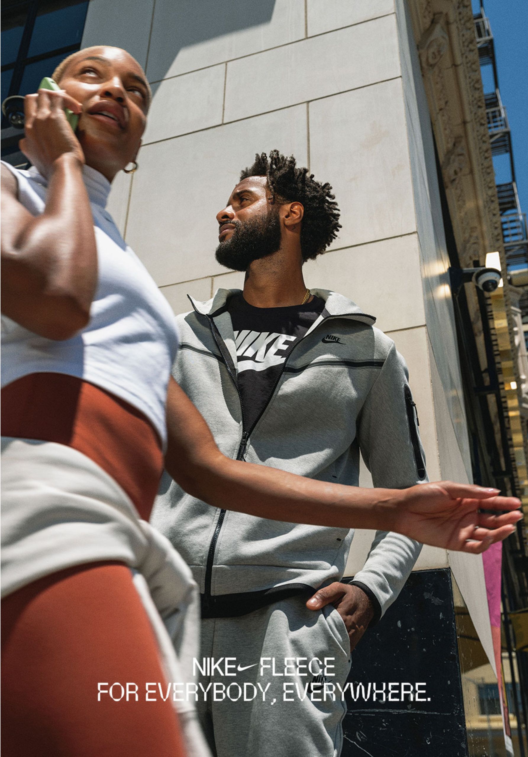 Women on phone passing man on street corner. Nike Fleece for everybody, everywhere