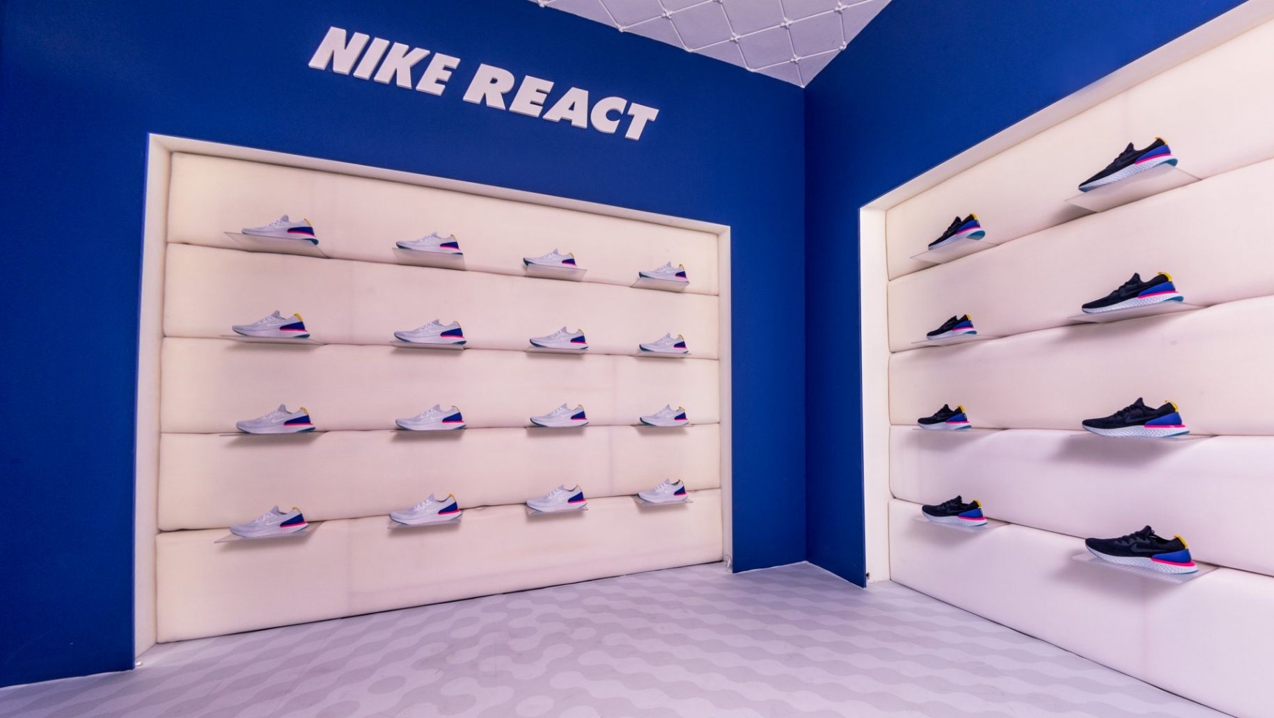 Installation walls where one displays rows of white colorway Nike React sneaker. Second wall displays rows of Blue Nike React colorway.