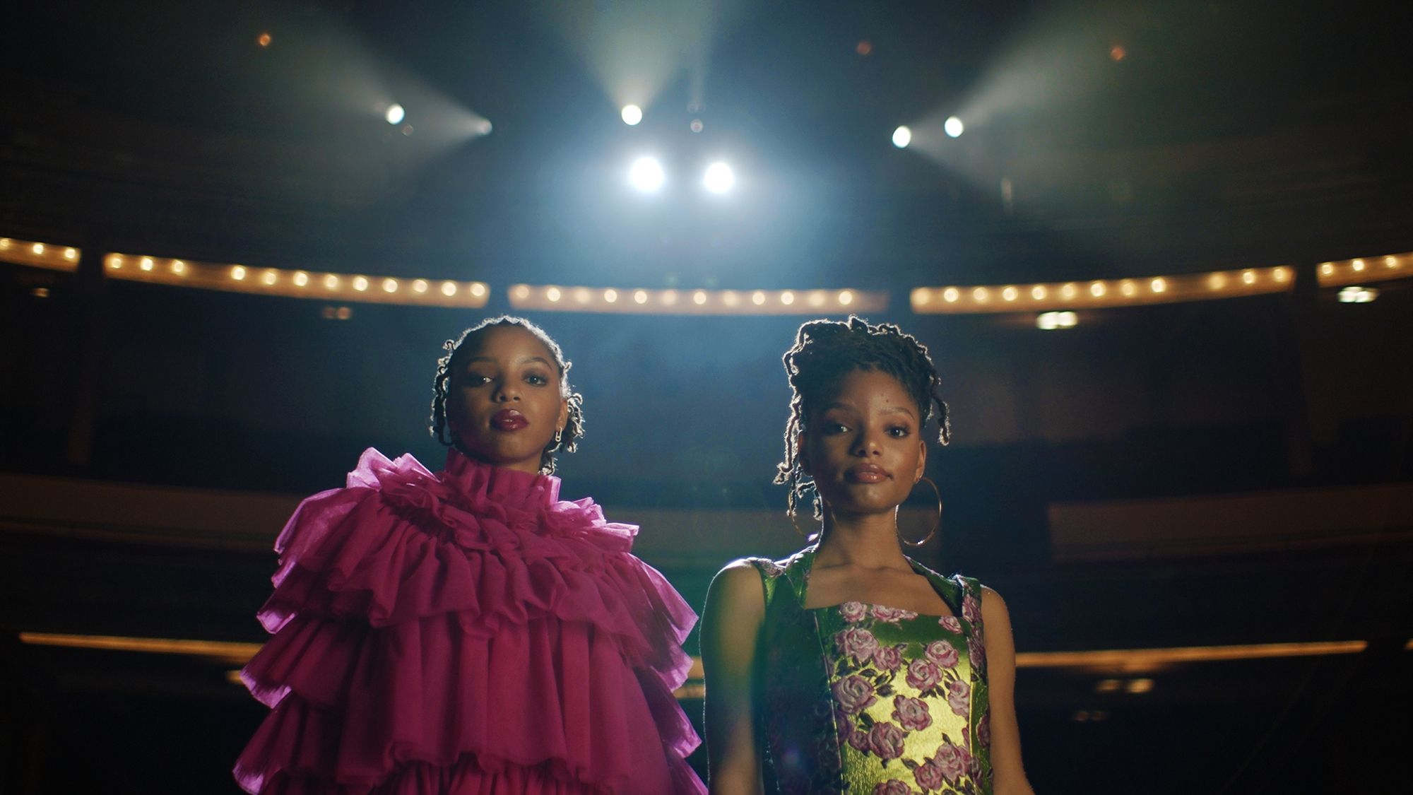 2 women, Chloe and Halle, on stage with lights and balcony behind them
