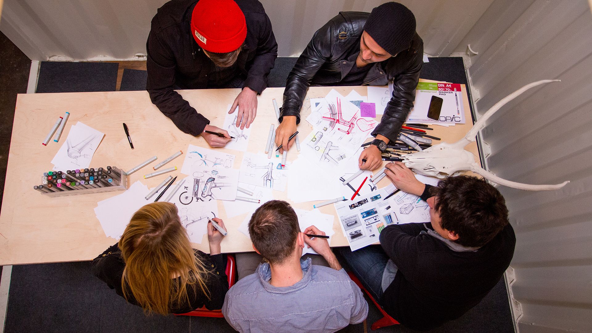 shot from above 5 people mark up sketches of a bicycle design