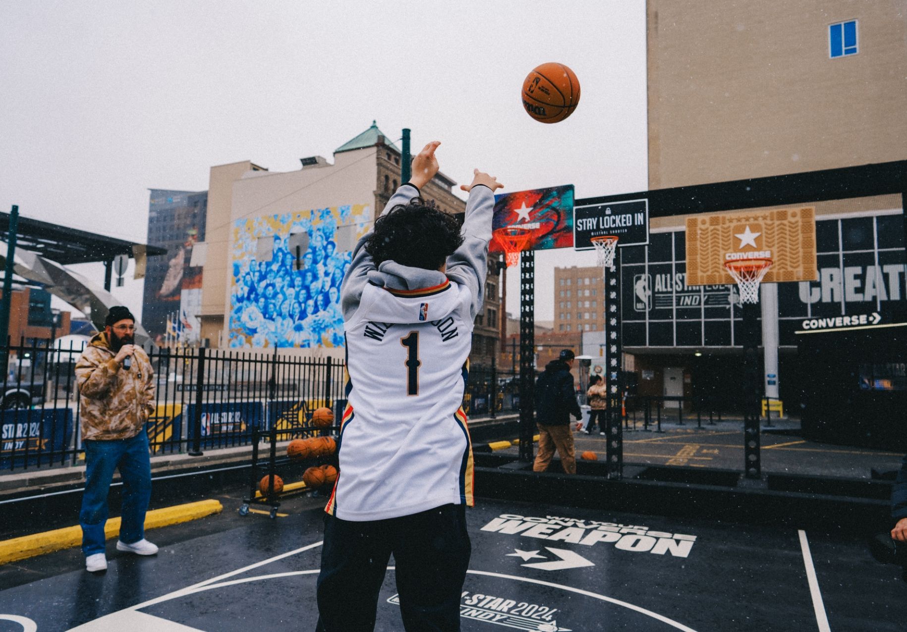 Shot from behind of man shooting basketball towards 3 artist created backboard and hoops