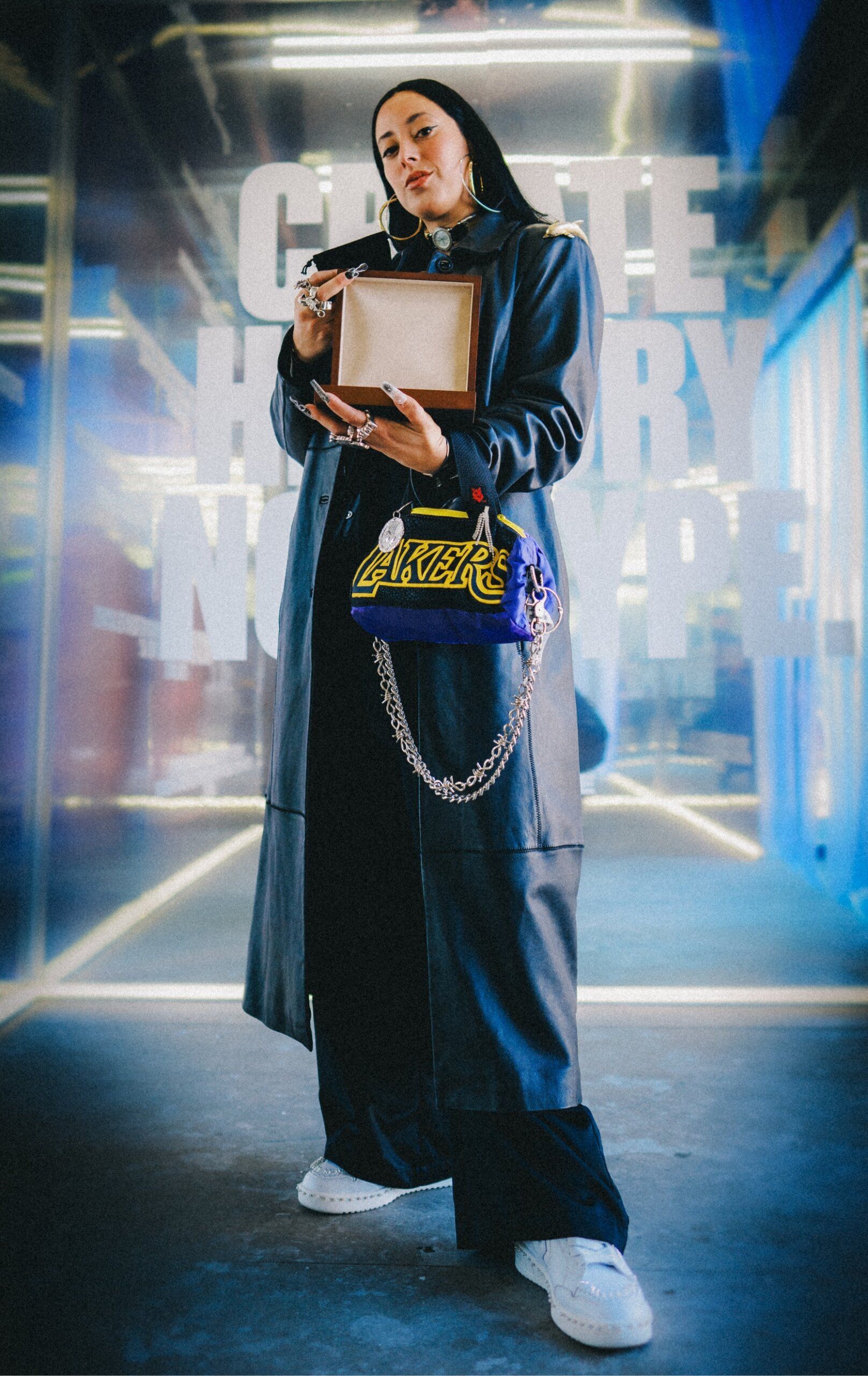 Artist,Georgina , stands displaying her jewels wearing Lakers gear and her custom jeweled Converse sneakers