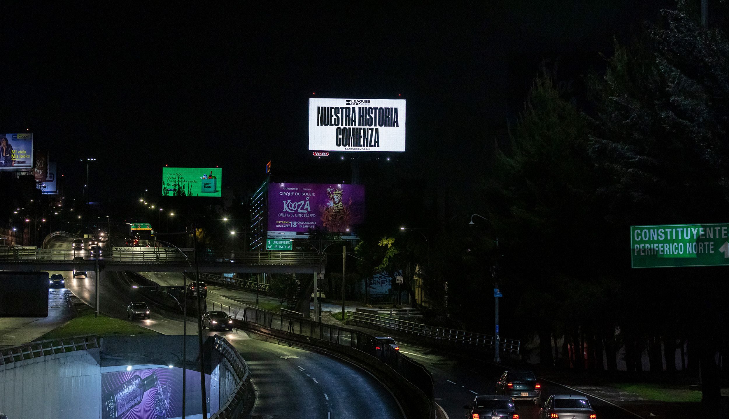 Nuestra Historia Comenza light up billboard over a highway at night in Mexico
