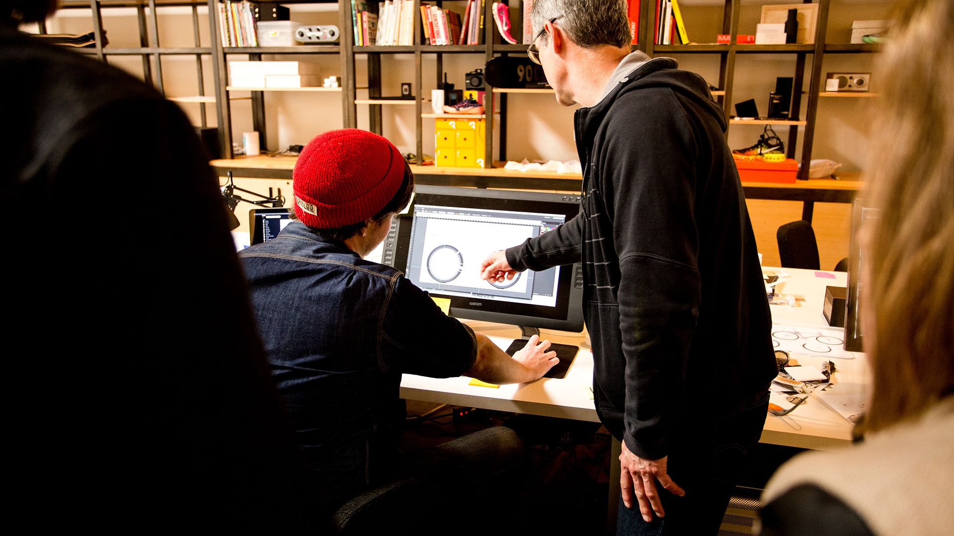 two people look at a 3d rendering of a bicycle on a computer monitor