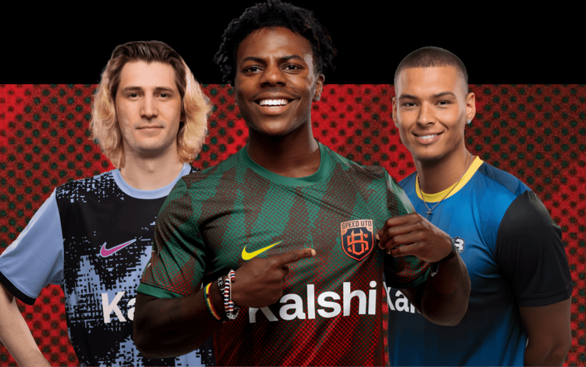 Three young men in soccer jerseys stand side by side, smiling at the camera. The central figure points to his chest, displaying a “Speed Utd” badge on his green and red shirt.