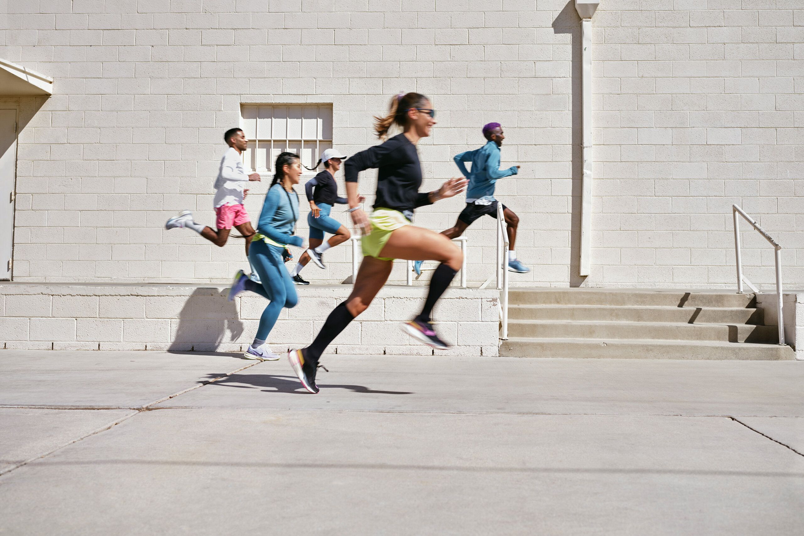 Group of women running on concrete in front of white building
