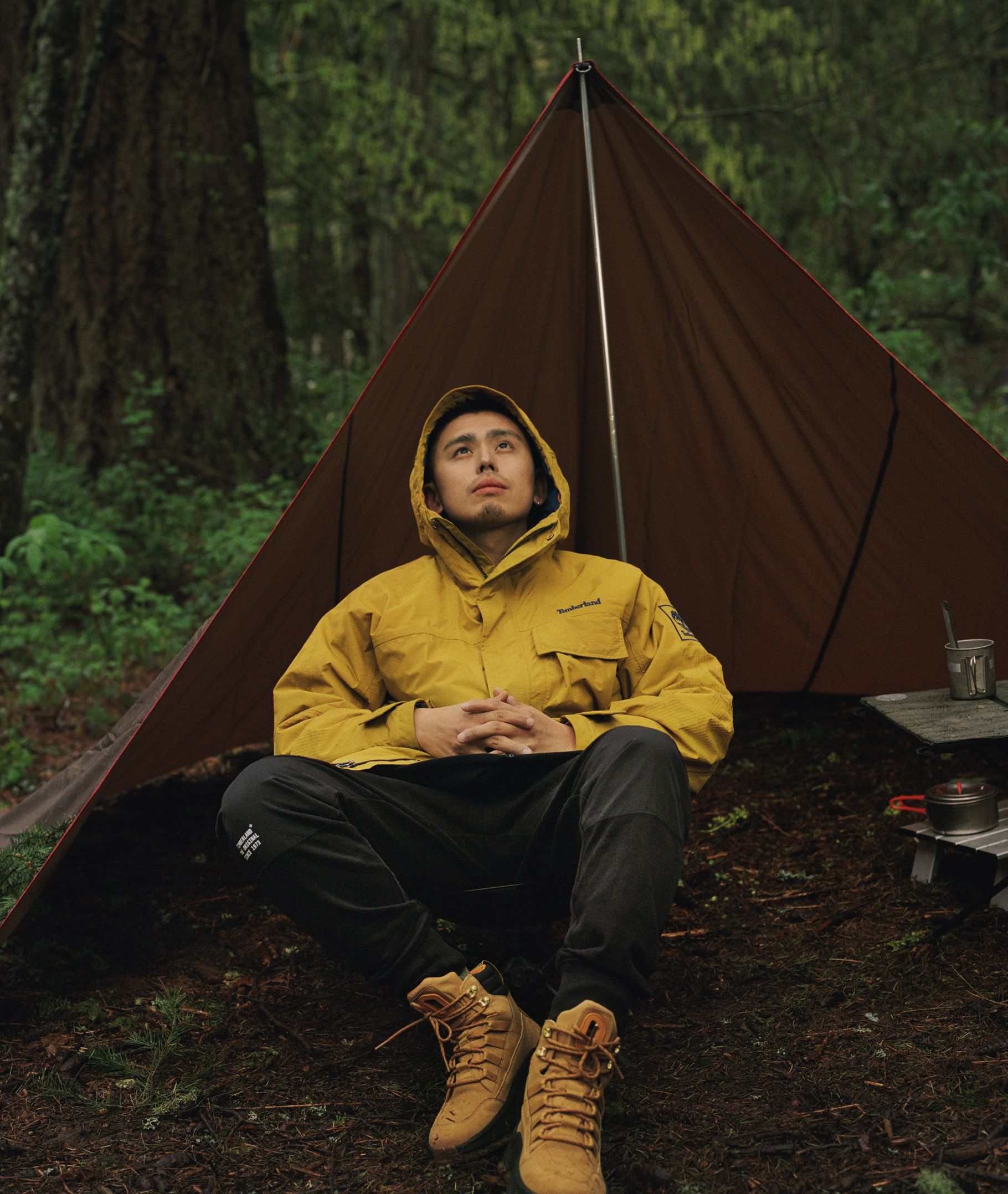 man in woods sitting in front of tent with Timberland boots on