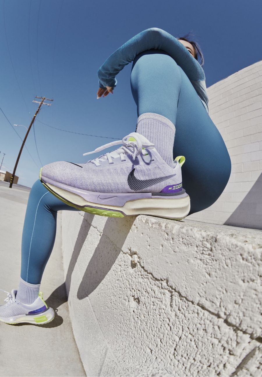 Runner sitting on concrete ledge with foot wearing Nike Invincible 3 on ledge and main focus