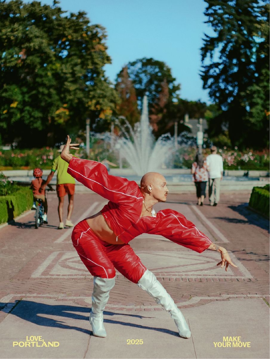 A person in a red quilted outfit and white boots strikes a dance pose on a park path in front of a fountain, with trees and people in the background.