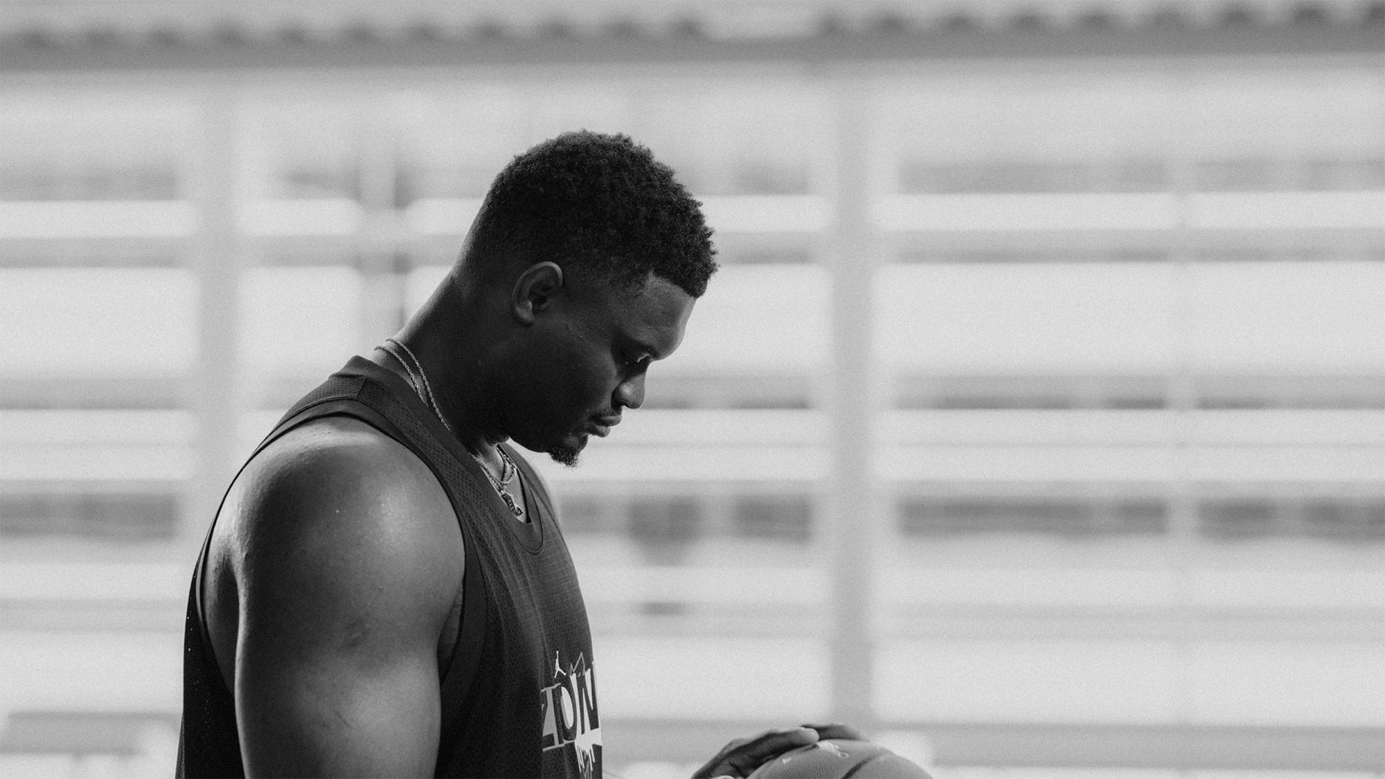 Black and White side view of Zion Williamson holding basketball looking down with eyes closed