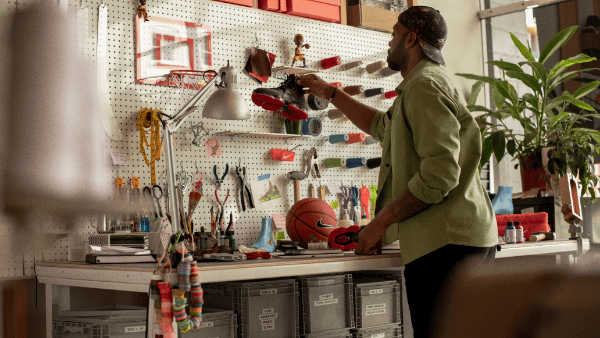 Tim Day holding Lebron XIX shoe against his work bench pegboard.