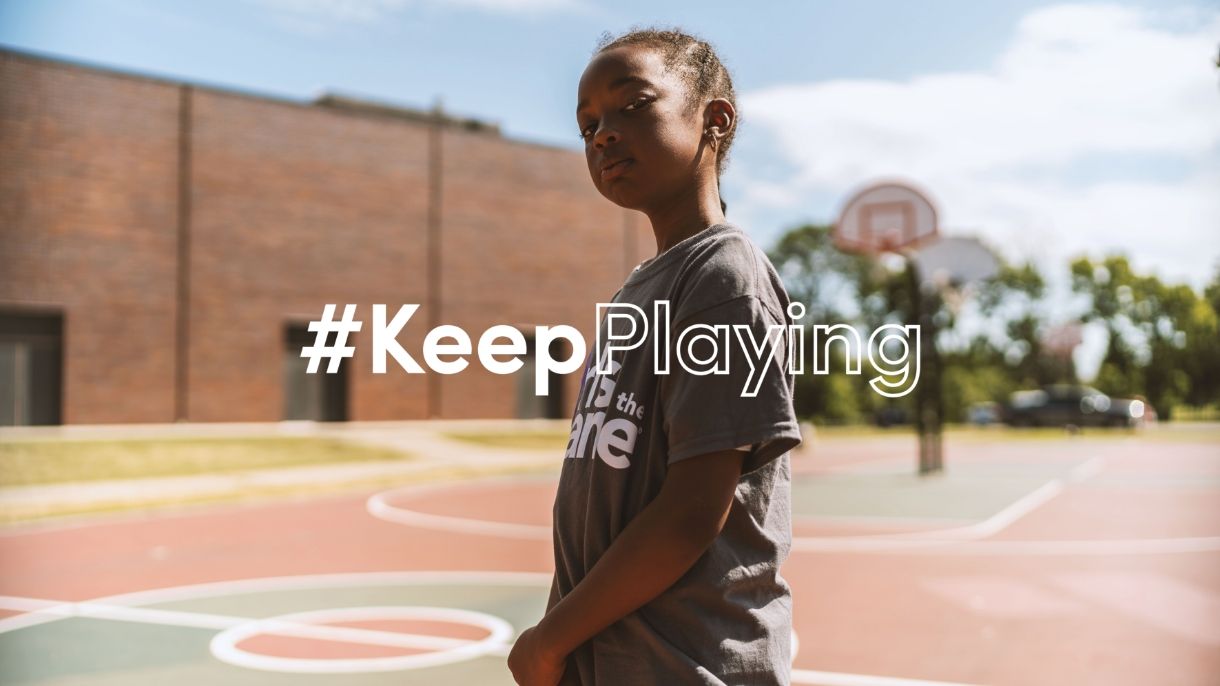 girl standing on basketball court with #KeepPlayingg